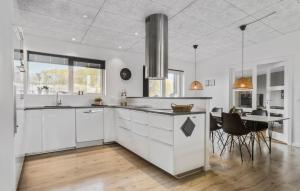 a kitchen with white cabinets and a dining table at Four-Bedroom Holiday Home Haderslev With A Room Hot Tub 09 in Knud
