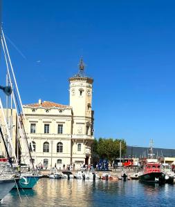 a building with a clock tower next to a marina at l'Alceste in La Ciotat +7 photos