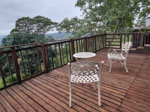 two chairs and a table on a wooden deck at 11-on-RobRoy serenity glamping cabins overlooking the Valley of 1000 Hills in Hillcrest