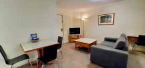 sala de estar con sofá, mesa y silla en Cbd Perth A Gem 1bedroom Apartment, en Perth
