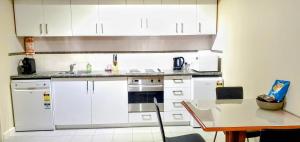 cocina con armarios blancos y mesa en Cbd Perth A Gem 1bedroom Apartment, en Perth