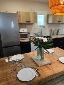 una mesa de madera con platos y vasos y un jarrón de flores en Jolie maison Ares, en Arès
