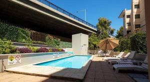 una piscina con tumbonas y sombrilla en Cbd Perth A Gem 1bedroom Apartment, en Perth