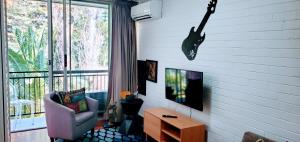 uma sala de estar com uma guitarra pendurada na parede em Quaint & Tranquil Subiaco 1 Bedroom Apartment em Perth
