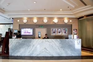 a lobby with a counter with clocks on the wall at Dubai Grand Hotel by Fortune, Dubai Airport in Dubai