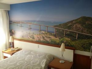 a bedroom with a painting of a bridge on the wall at Pasargada Praia da Costa in Vila Velha