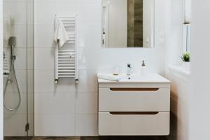 y baño blanco con lavabo y ducha. en APARTAMENTY LAS Zator en Zator