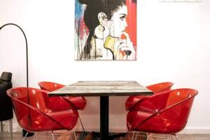 une table avec des chaises rouges et un tableau sur le mur dans l'établissement Serenity And Comfort In Subiaco 1 Bedroom Unit, à Perth