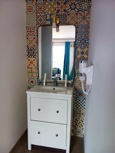 La salle de bains est pourvue d'un lavabo blanc et d'un miroir. dans l'établissement Tangara, à Villars-les-Dombes