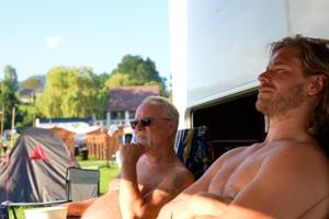 dos hombres sin camisa sentados en sillas de jardín en una playa en Schitterhof CAMPING WEISS, en Spielberg