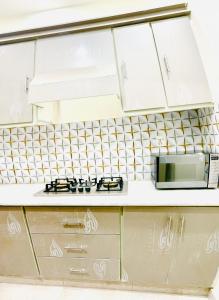 a kitchen with white cabinets and a stove top oven at Sj Luxury Suits in Lahore