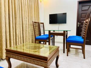 a living room with a table and chairs and a tv at Sj Luxury Suits in Lahore