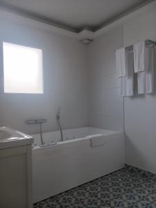 baño blanco con bañera y ventana en Quetzal, en Villars-les-Dombes