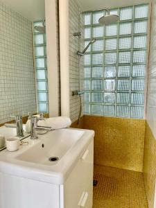 La salle de bains blanche est pourvue d'un lavabo et d'une douche. dans l'établissement La Mer à Pied appartement vue mer, à Dieppe