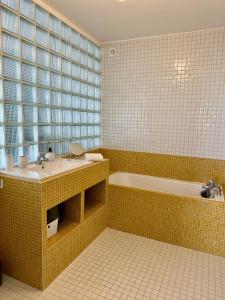 La salle de bains est pourvue de carrelage jaune, d'un lavabo et d'une baignoire. dans l'établissement La Mer à Pied appartement vue mer, à Dieppe
