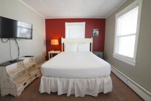 a bedroom with a white bed and a flat screen tv at North Beach Hotel in Ventnor City
