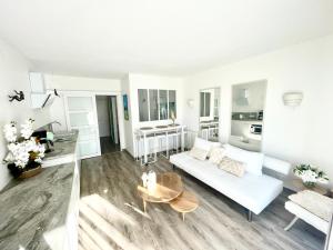 ein Wohnzimmer mit einem weißen Sofa und einem Tisch in der Unterkunft Oasis près du Golf avec piscine et parking in Anglet