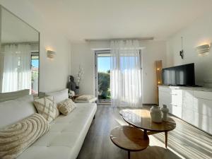 een woonkamer met een witte bank en een tv bij Oasis près du Golf avec piscine et parking in Anglet