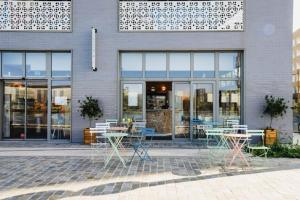 a store with tables and chairs in front of a building at Peaceful green setting near to Paris Center in Pantin