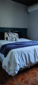 uma cama com um cobertor azul e almofadas em Residência Vô José - Casa 02 em Pomerode