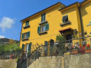 a yellow building with windows and flowers on a fence at Casa vacanze Dolce Glicine in Bonassola