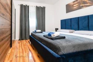 a bedroom with a large bed with a blue headboard at Apartment Black Diamond in Ražanac +93 photos