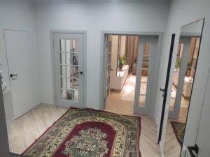 een kamer met een tapijt op de vloer en een open deur bij Элитная квартира со всеми удобствами в центре города Каракол in Karakol