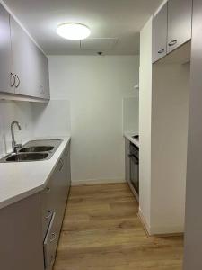 a white kitchen with a sink and a stove at Darling harbour & ICC & CBD & Chinatown & Spacious in Sydney