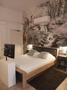 1 dormitorio con 1 cama y una pintura en la pared en Calao, en Villars-les-Dombes