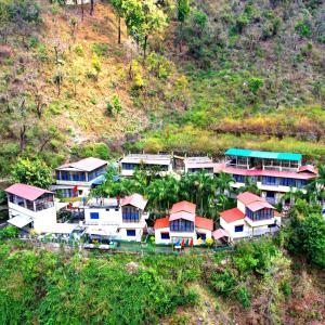 Vue aérienne d'un groupe de maisons sur une colline dans l'établissement Baandal River Resort Maldevta, à Kokliyal Gaon