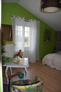 Domaine chez Maurice في Bécheresse: غرفة خضراء مع طاولة وسرير ونافذة