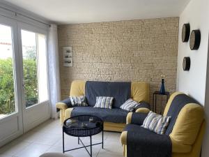 a living room with a couch and a brick wall at Gite Thym spa au coeur d'une oliveraie des Corbières in Saint-Jean-de-Barrou
