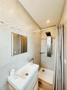 La salle de bains est pourvue d'un lavabo, d'une baignoire et d'une douche. dans l'établissement Residence Canella, à Sari-Solenzara