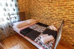 Cama pequeña en habitación con pared de ladrillo en Book Hotel, en Kutaisi