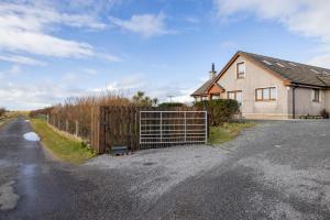 een huis met een hek aan de kant van een weg bij Ard Buidhe B&B in Daliburgh