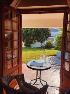 Eine Glastür führt auf eine Terrasse mit einem Tisch und Stühlen. in der Unterkunft Kanaloa Caparica Surf Lodge in Charneca