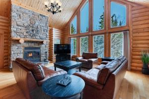 sala de estar con muebles de cuero y chimenea de piedra. en Fiddler Lake Resort Chalet 48 Deer, en Mille-Isles