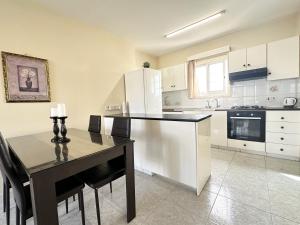 a kitchen with a table and a white refrigerator at Serenity Sunrise Holiday Apt - Larnaca in Larnaka