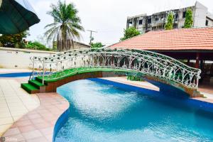 uma ponte sobre uma piscina de água ao lado de um edifício em New Green Horse Hotel em Cotonou