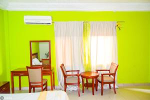 Habitación con mesa, sillas y pared verde. en New Green Horse Hotel, en Cotonou