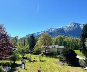 a house in a field with mountains in the background at Ferienwohnungen Quellenhof in Bad Reichenhall