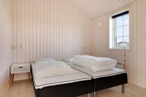 two beds in a white room with a window at Havnsø med udsigt in Føllenslev