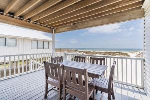 a wooden table and chairs on a deck with the beach at Bonhomme Richard East in Gulf Shores