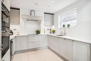 a white kitchen with white cabinets and a sink at Oakdale & The Regal at Latchmere Hse in Richmond