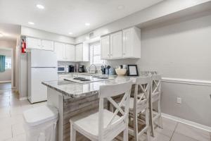 a kitchen with white cabinets and a island with bar stools at Bonhomme Richard East in Gulf Shores