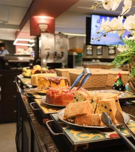 una línea de buffet con platos de pan y pasteles en Hotel Imperatriz, en Telêmaco Borba