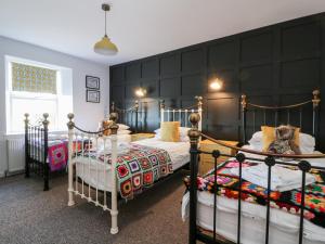 2 camas individuales en un dormitorio con una pared negra en Smithy House, en Dumfries