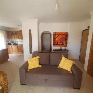 a living room with a brown couch and yellow pillows at Pérola do Sol in Vila Real de Santo António