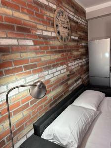 a brick wall with a bed and a clock on it at HappyHome Rivarolo 6 posti letto in Rivarolo Canavese