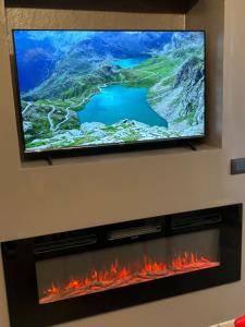 a flat screen tv above a fireplace with flames at HappyHome Rivarolo 6 posti letto in Rivarolo Canavese